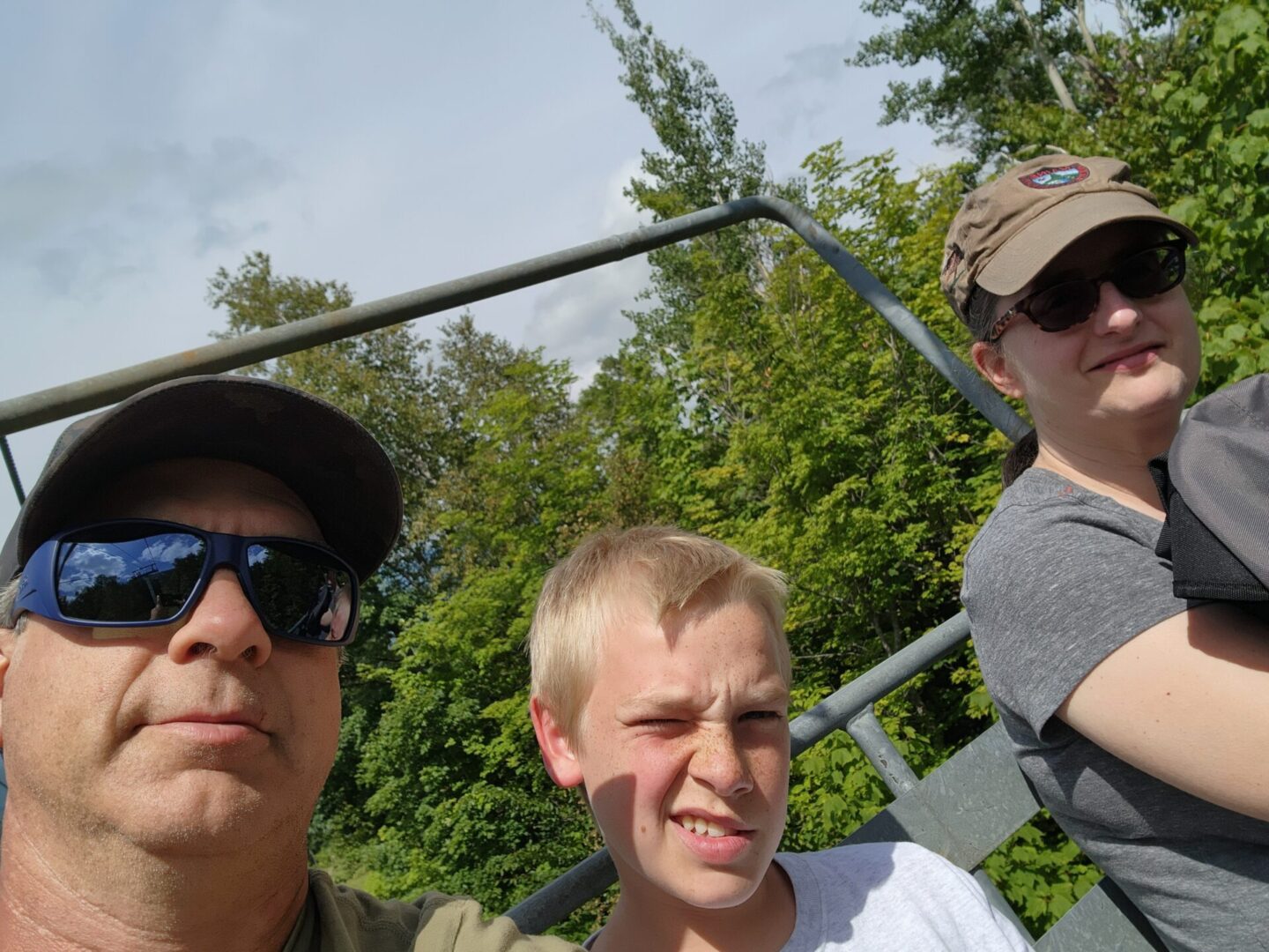 Three men are standing together in a park.