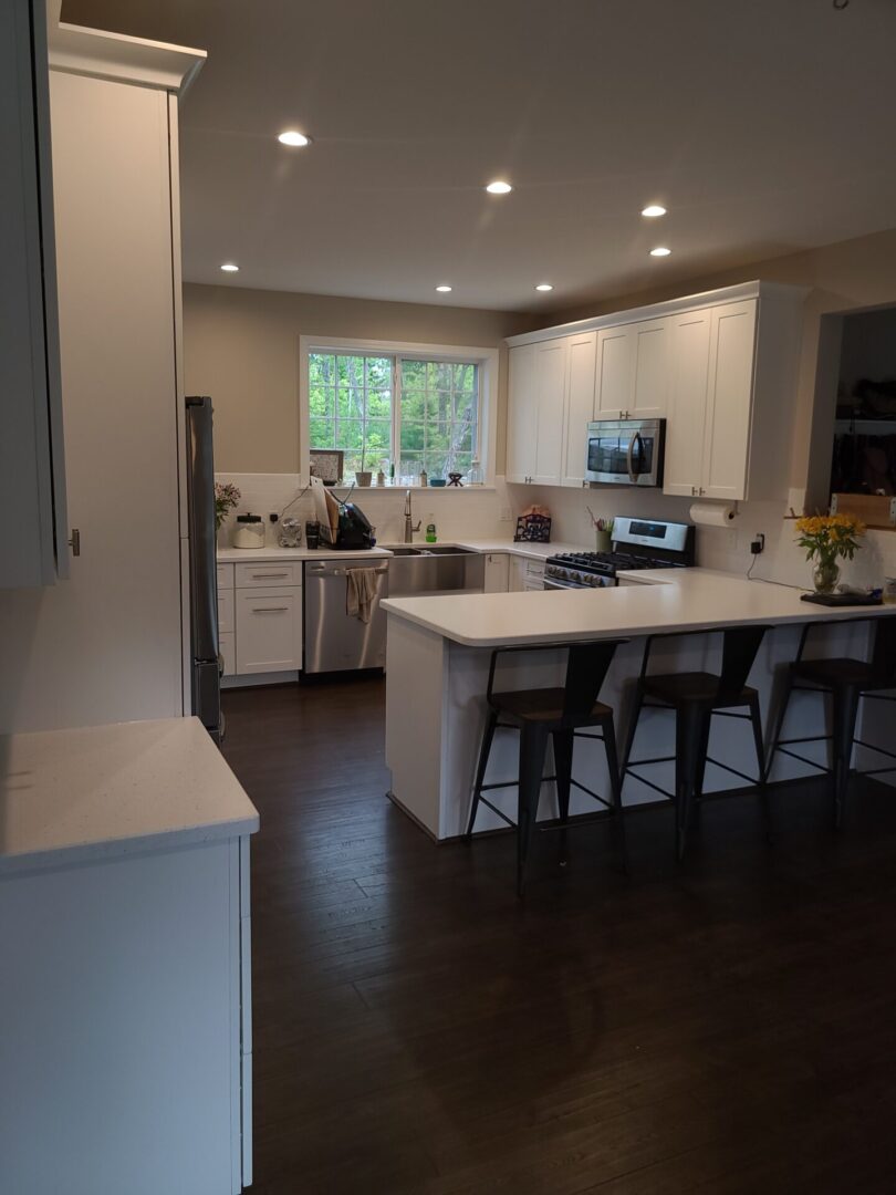 A kitchen with white cabinets and black counter tops.