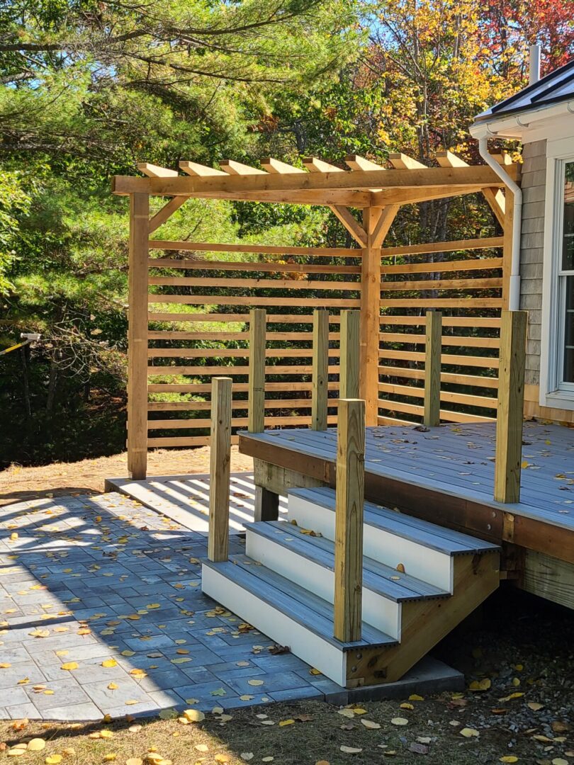 A wooden pergola over the back of a deck.