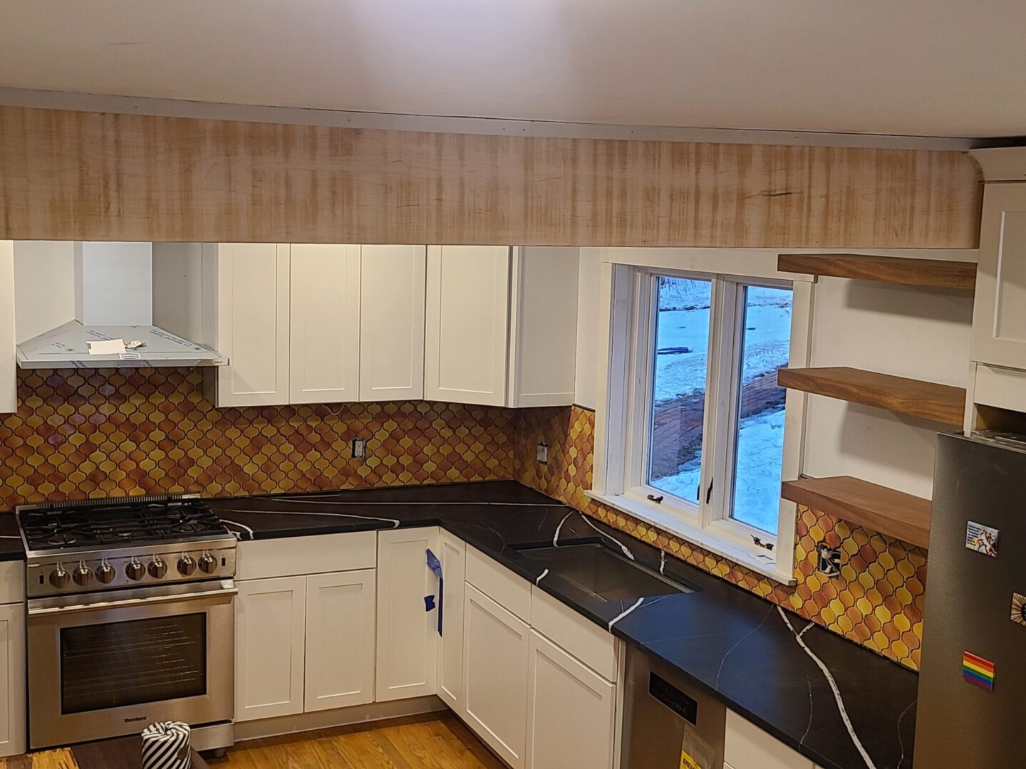 A kitchen with white cabinets and black counter tops.