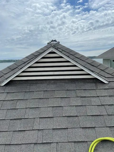 A roof with a triangle shaped vent on it.