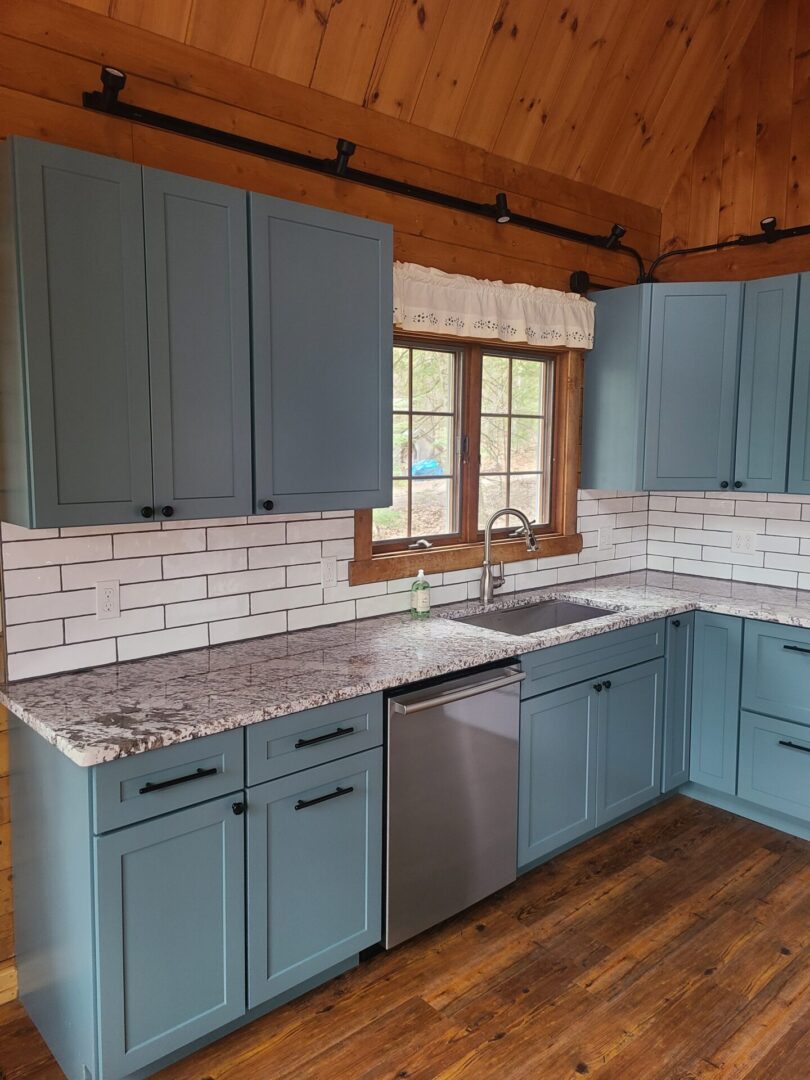 A kitchen with blue cabinets and white tile walls.