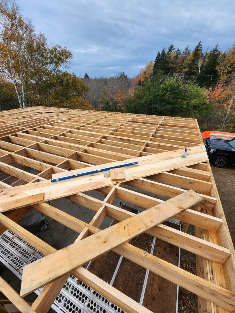 A wooden structure being built with some trees in the background.